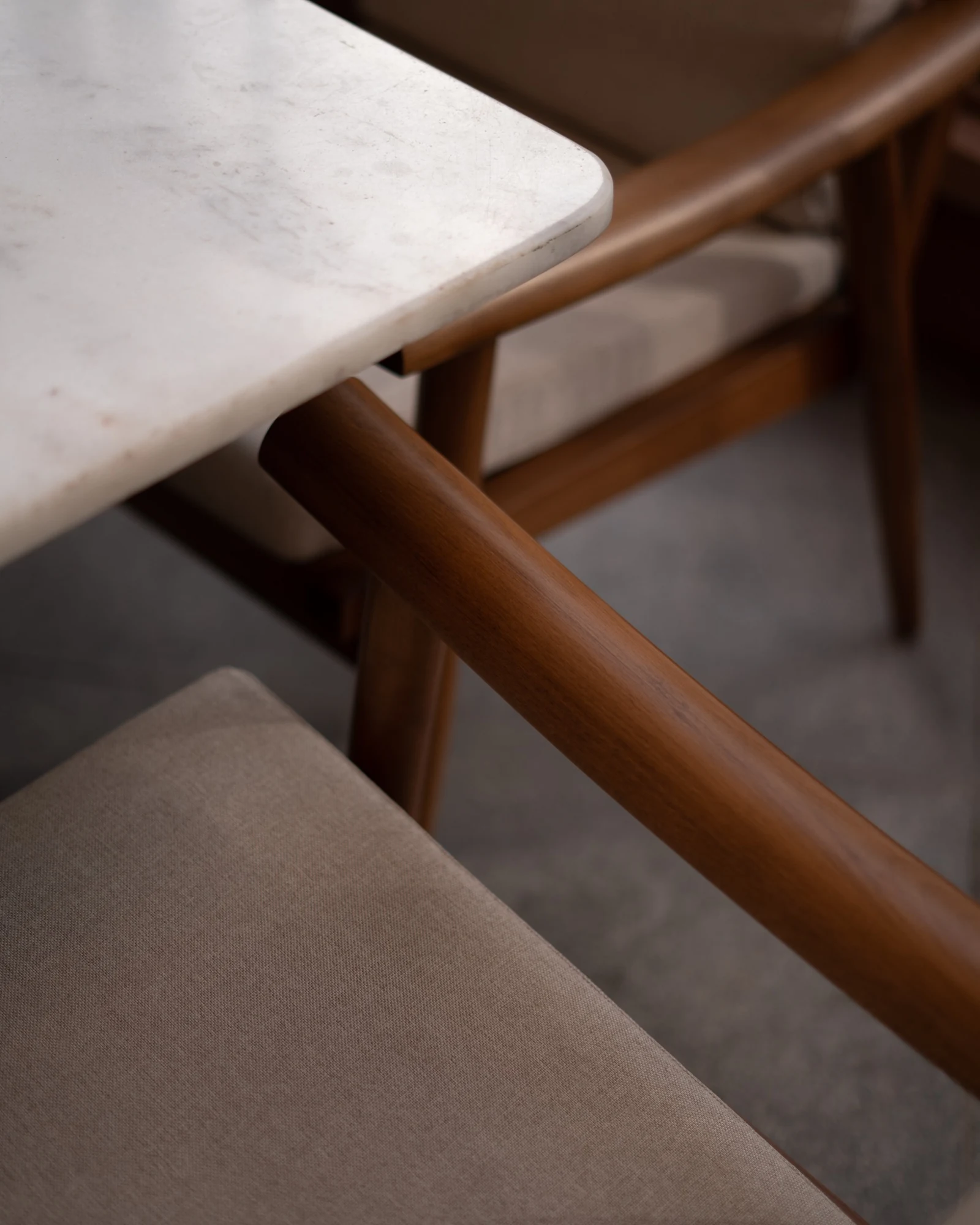 Detail of a timber armrest, upholstered seat and stone tabletop