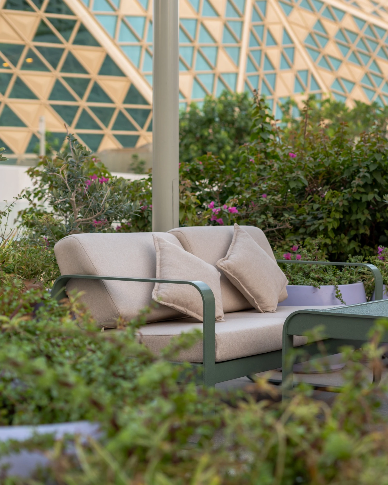 Green outdoor lounge seating surrounded by planting