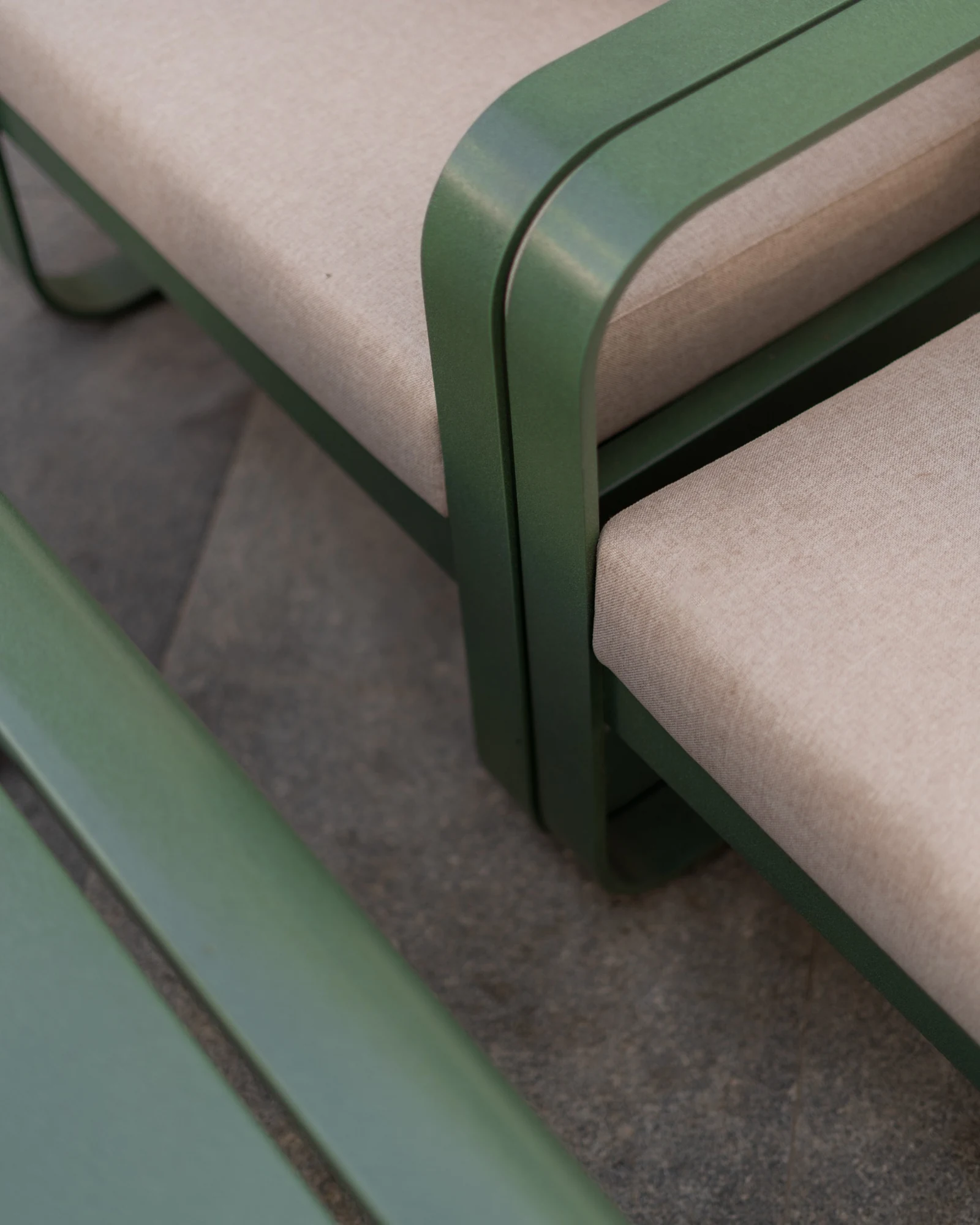 Detail of green metal chair frames and neutral upholstery